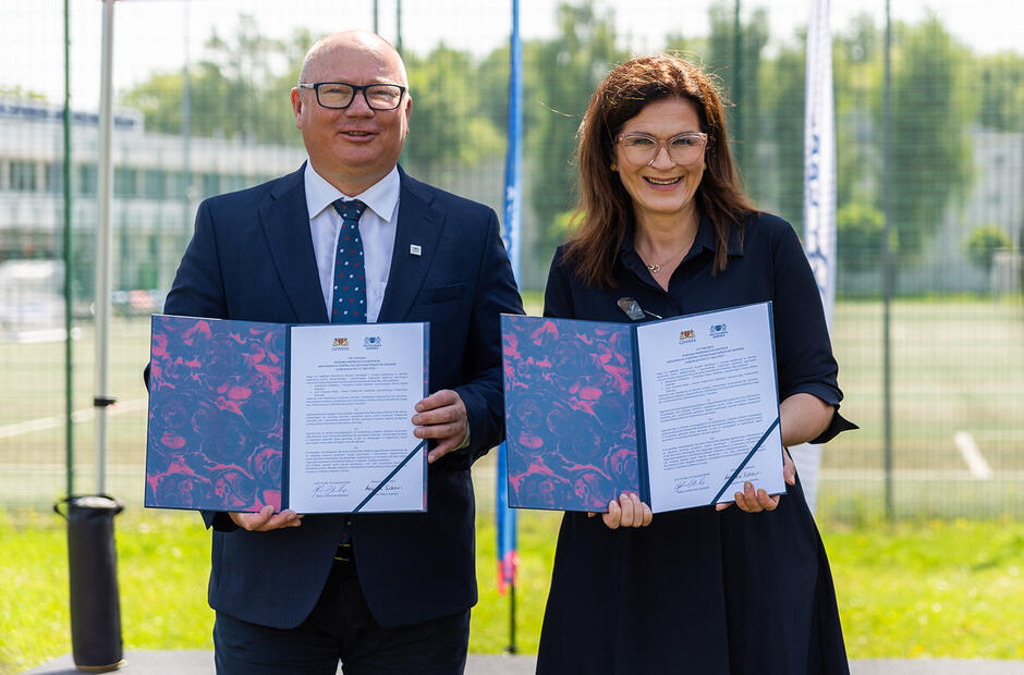 Kobieta i mężczyzna pozują do fotografii, uśmiechają się i trzymają w rękach podpisany list intencyjny.