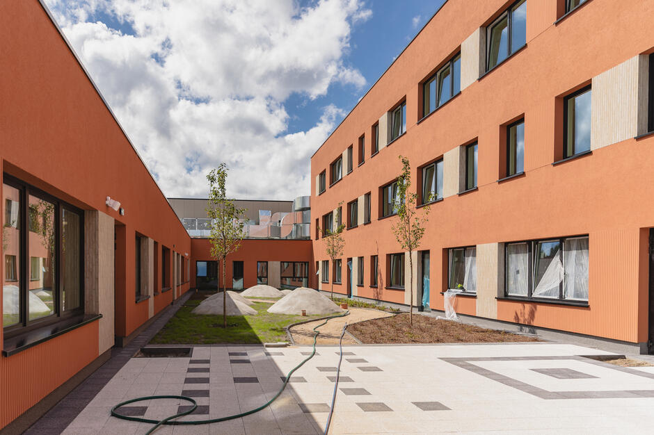 wnętrze budynku o elewacji w kolorze ceglanym, widać nowe patio