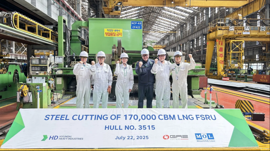 na zdjęciu wnętrze stoczni, widać dużo rur, po środku pozuje sześć osób w jasnych kombinezonach