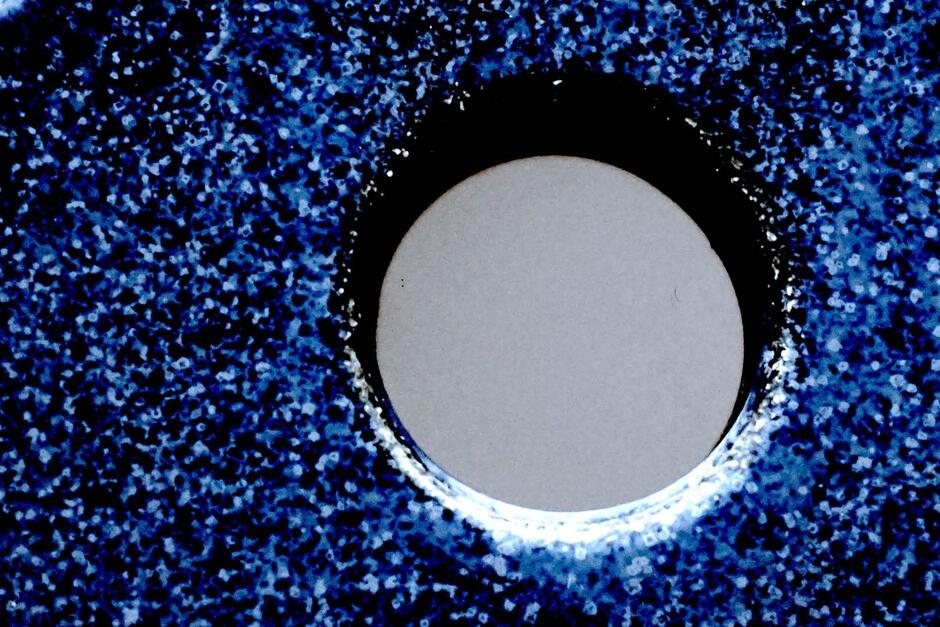 Zbliżenie na abstrakcyjny, niebiesko-biały wzór z okrągłym otworem pośrodku. Obraz przywodzi na myśl widok przez mikroskop lub lunetę.


