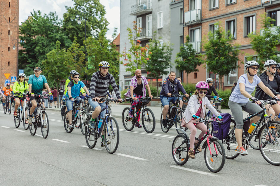 na zdjęciu kilkunastu rowerzystów jadących rowerami po ulicy