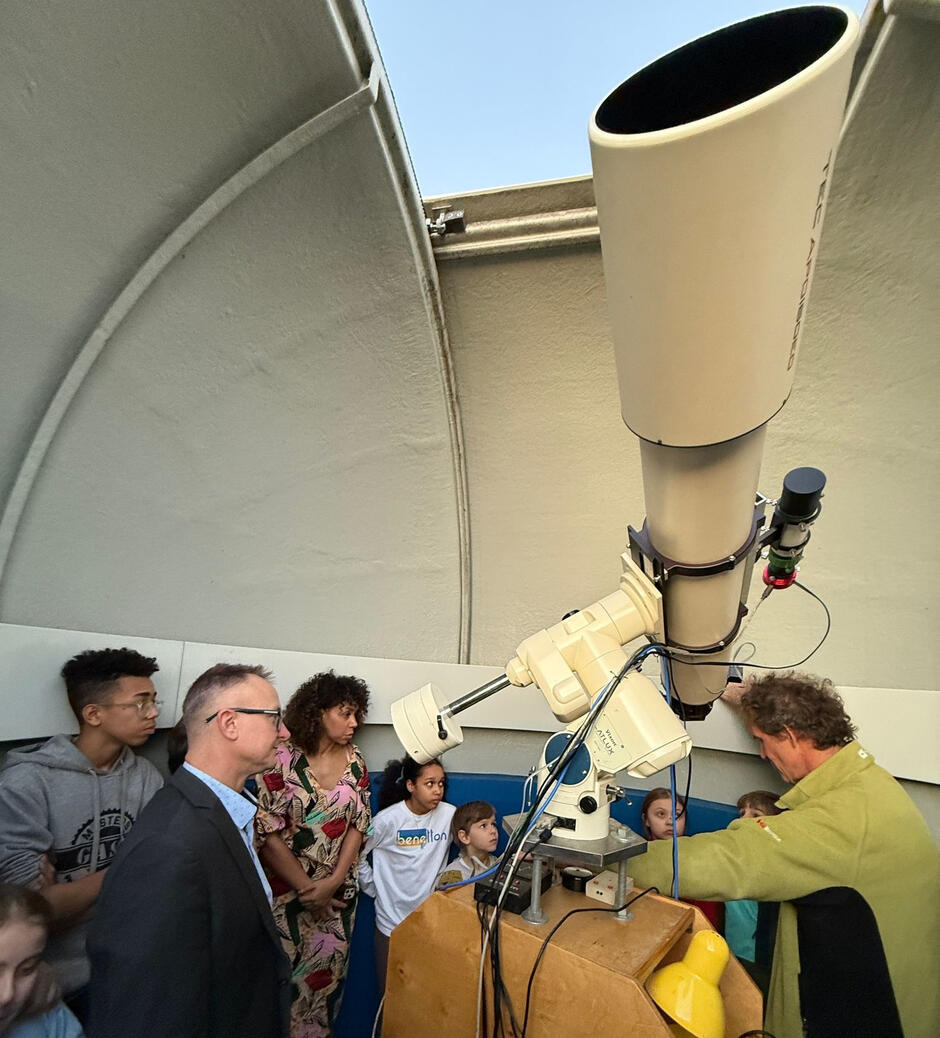 Ludzie zebrani wokół teleskopu w obserwatorium astronomicznym.