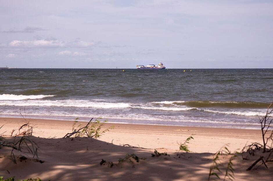 na zdjęciu plaża, zatoka, w oddali widać niewielki statek