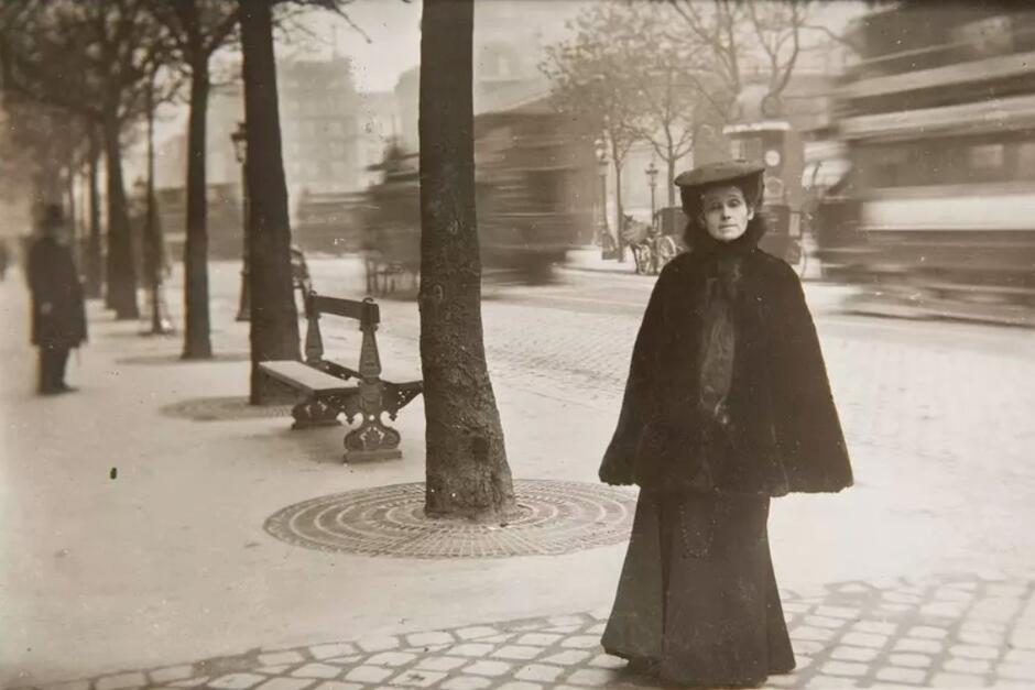 Stara fotografia w sepii, kobieta w czarnej sukni z epoki, pozuje do zdjęcia, stojąc na bulwarze