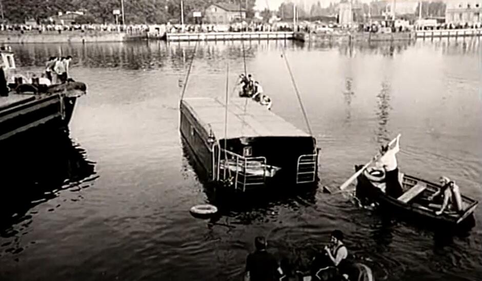 Widok wyłowionego z rzeki promu, który jest już na powierzchni, dzięki pracy dźwigu