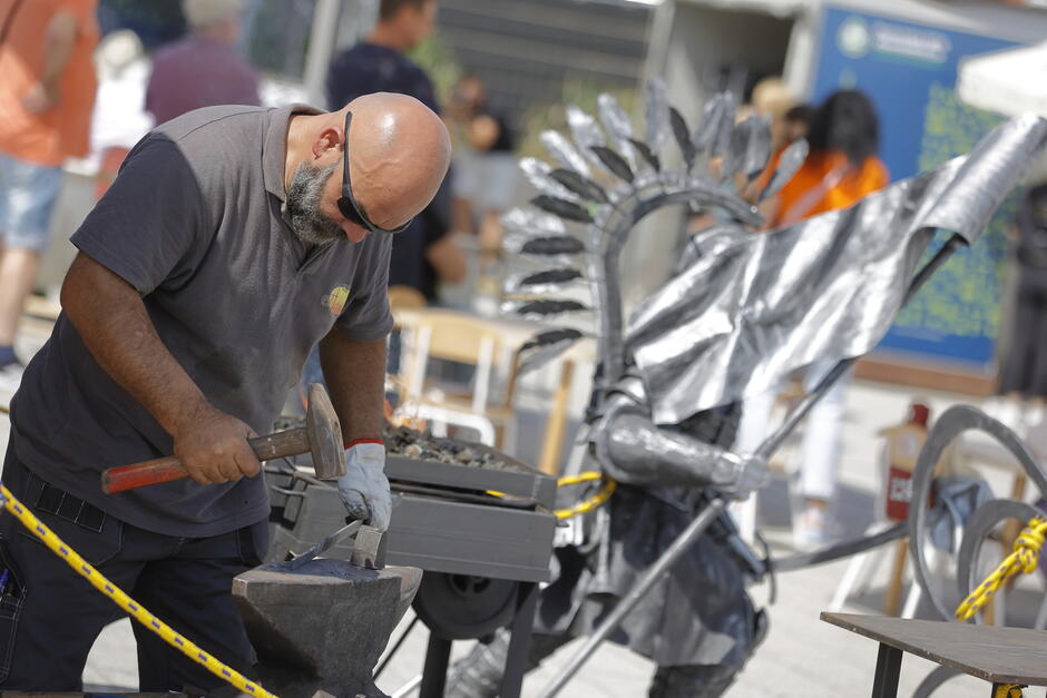 Rzemieślnik kowal robi pokaz swojej pracy na jarmarku w mieście.