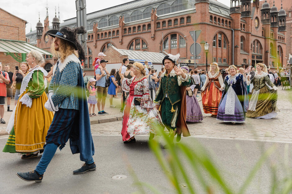 Parada ulicami starego miasta, w której idą ludzie przebrani w stroje z epoki.