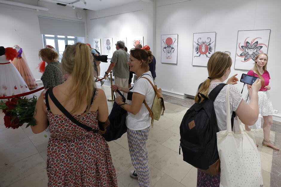 Ludzie oglądają wystawę ze sztuka ludową.