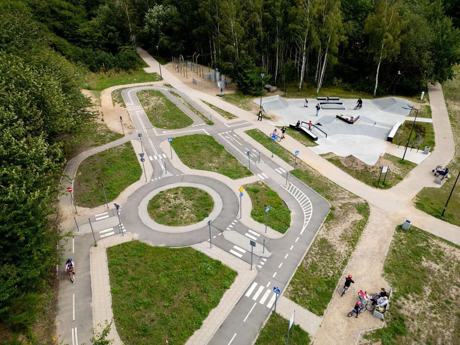 Zdjęcie z lotu ptaka na wielofunkcyjny park, widać skatepark i miasteczko ruchu drogowego, na alejkach ludzie.