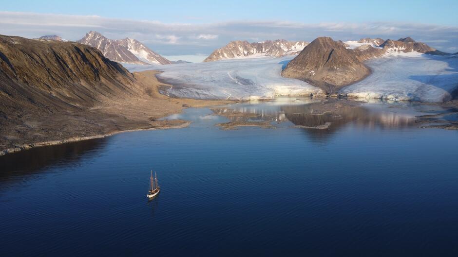 Zdjęcie z lotu ptaka, żaglowiec w fiordzie, w tle lodowiec.