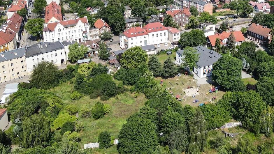 Zdjęcie z lotu ptaka, przedstawiająca zielony plac między budunkami