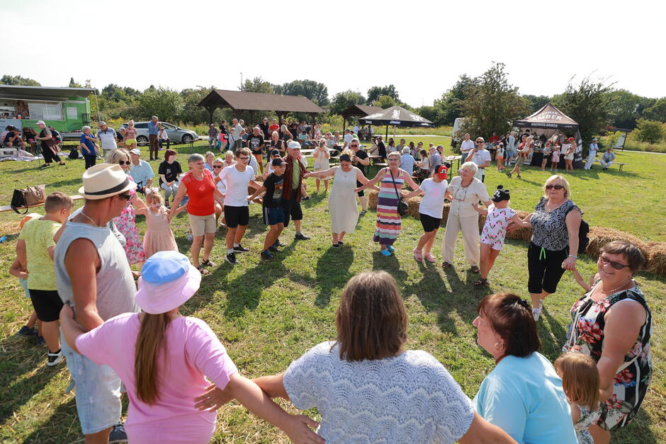 na zdjęciu grupa osób w różnym wieku, stoją w kole, bawią się