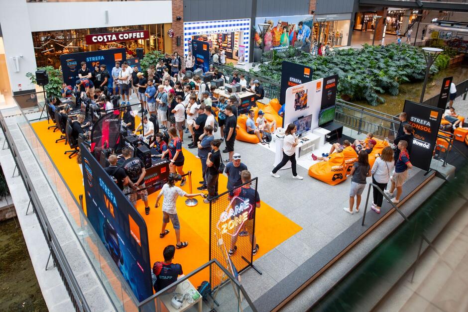 Strefa gier komputerowych w centrum handlowym, w której ludzie grają w różne gry.
