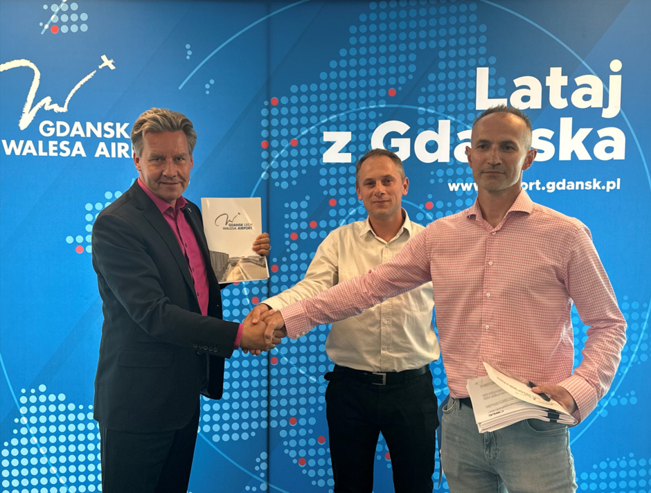 na zdjęciu trzech mężczyzn, dwóch podaje sobie ręce w ramach gratulacji