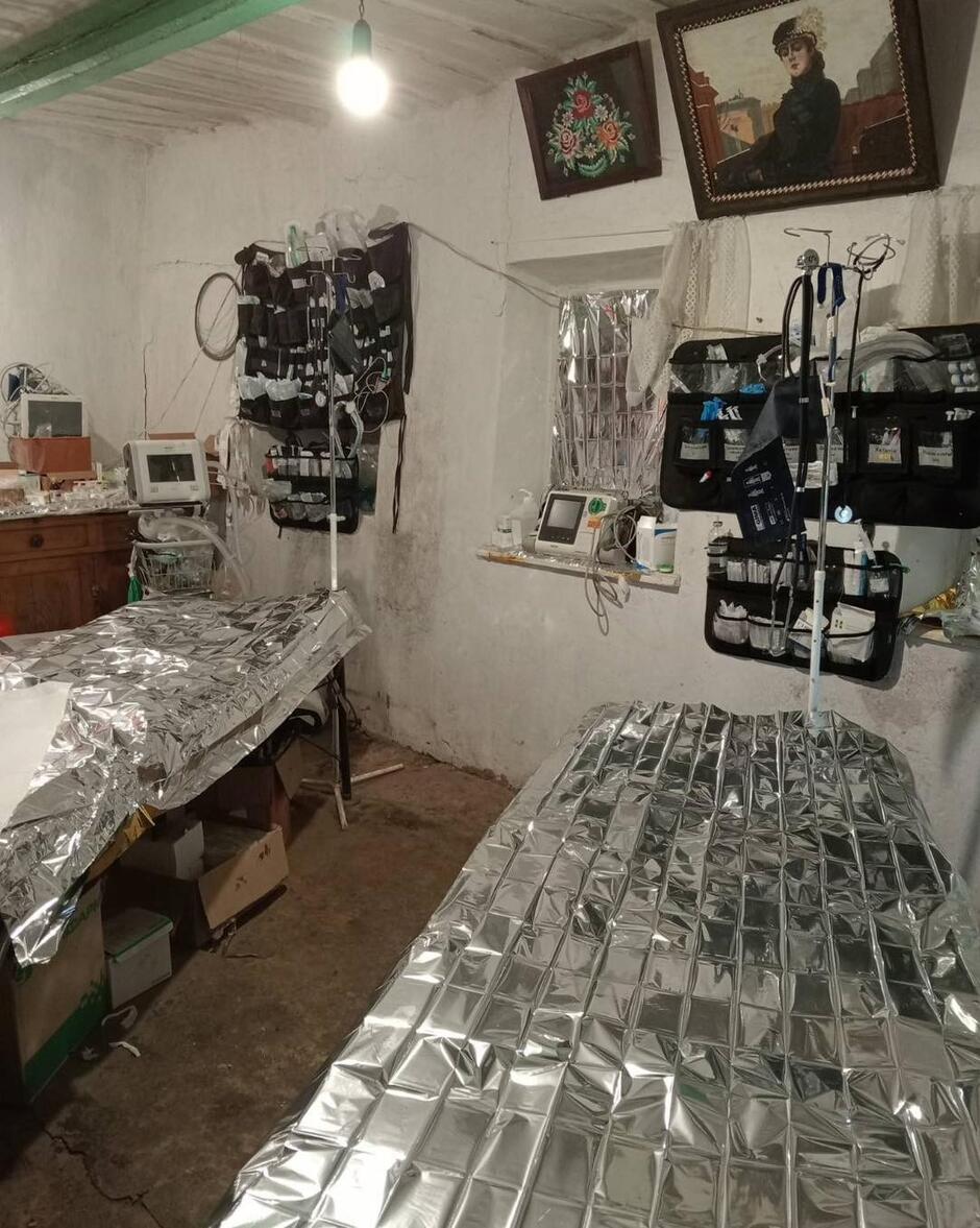 Dwa łóżka polowe z osprzętem medycznym w sali wiejskiego domu