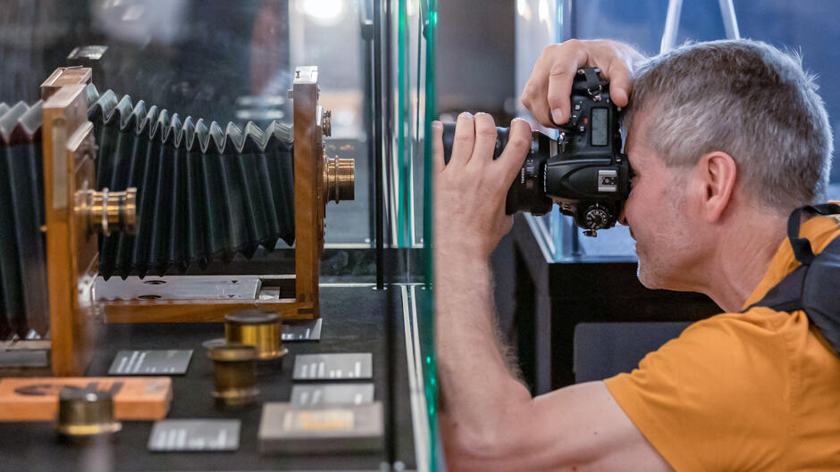 Mężczyzna robi zdjęcie starego aparatu fotograficznego na wystawie.