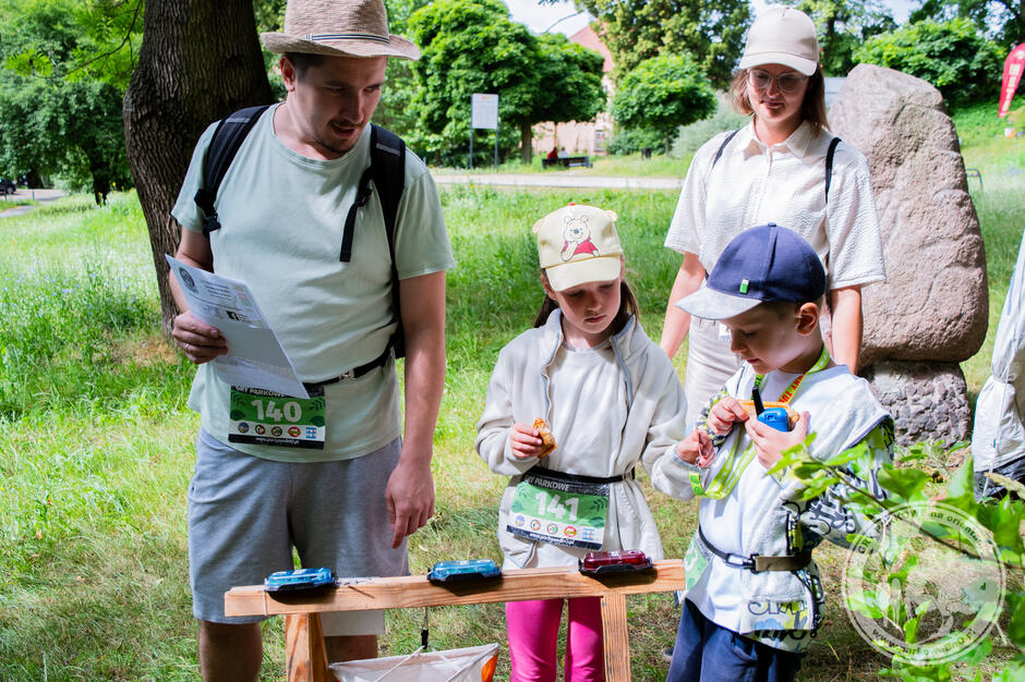 Młoda kobieta i młody mężczyzna z dwójką dzieci latem w parku biorą udział w grze terenowej.