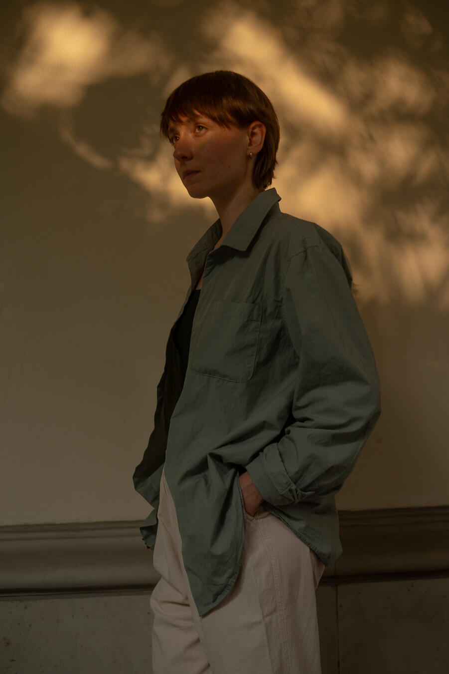 na zdjęciu kobieta o krótkich włosach, ubrana w koszulę i spodnie. 