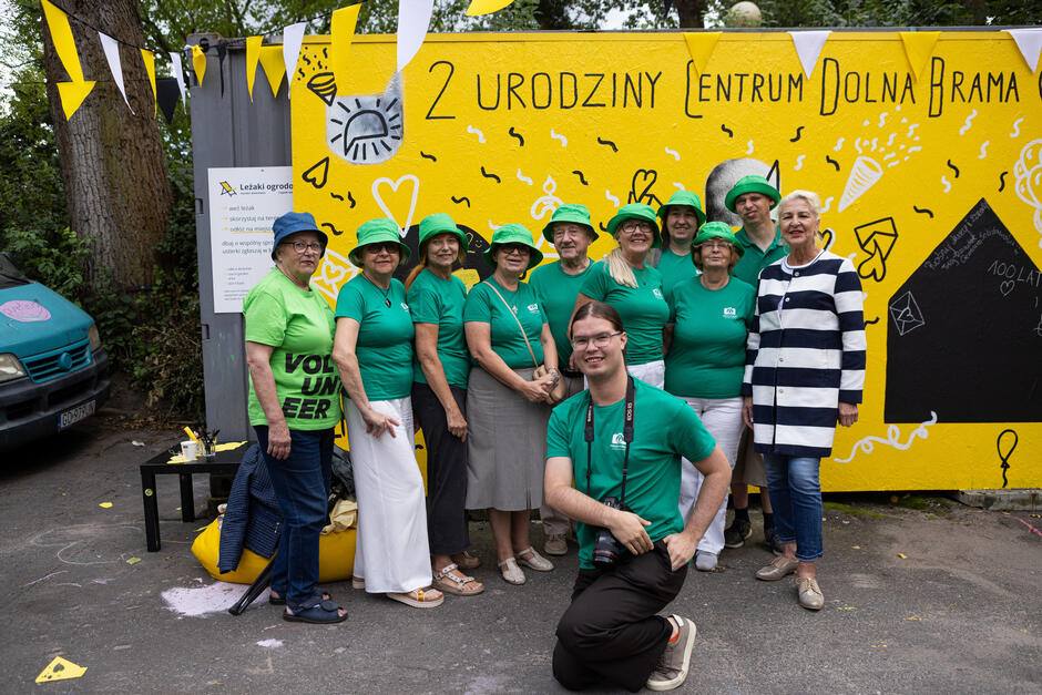 Grupa osób pozuje do zdjęcia pod ścianką.