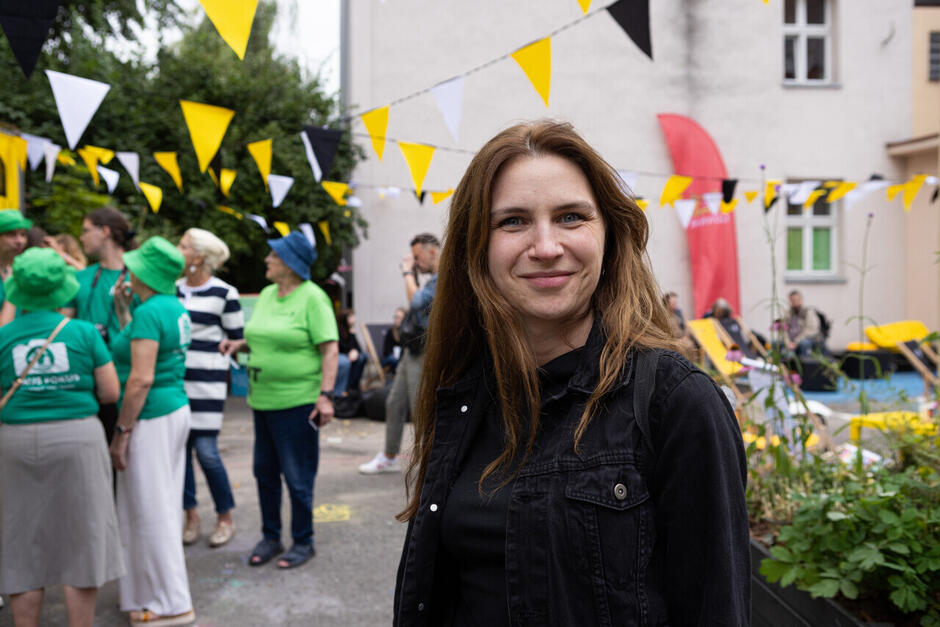 Młoda kobieta pozuje do zdjęcia po podwórku podczas wydarzenia.