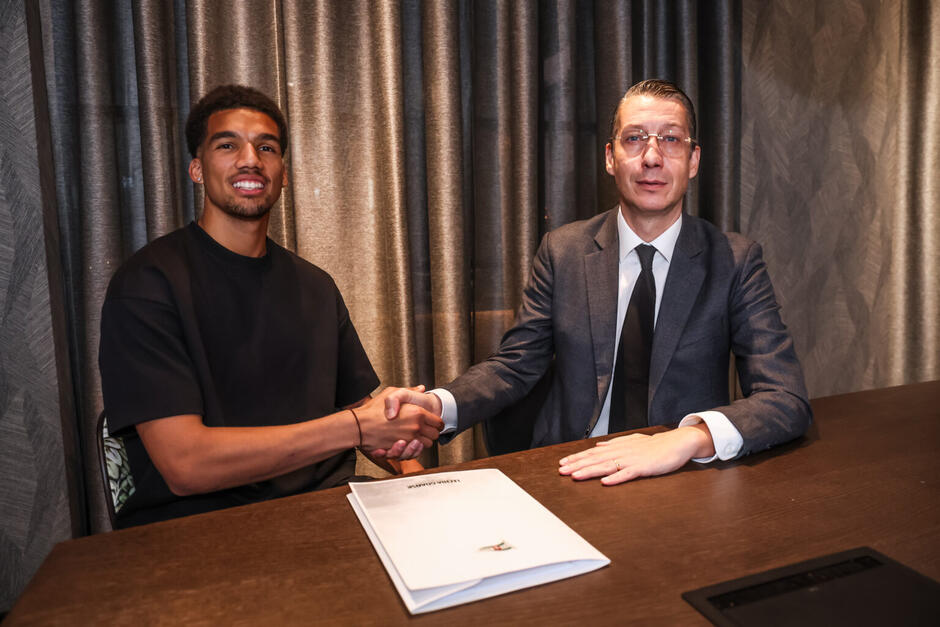 Dwaj mężczyźni pozują do zdjęcia, siedząc za biurkiem