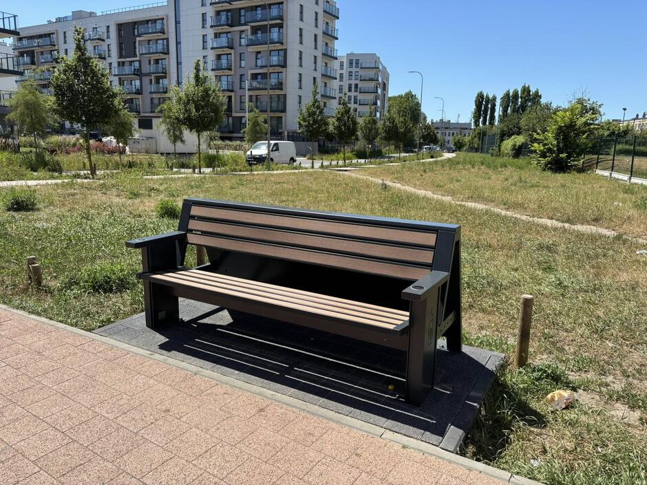 na zdjęciu drewniana brązowa ławka z czarnymi oparciami