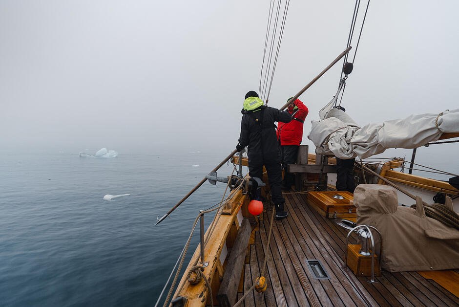 Żaglowiec płynie we mgle między dryfującym lodem, zdjęcie z pokładu.