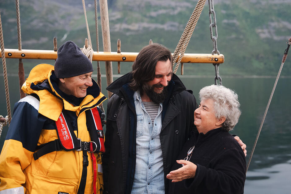 Młody kapitan statku z brodą ze starszymi osobami, kobietą i mężczyzną na pokładzie żaglowca.