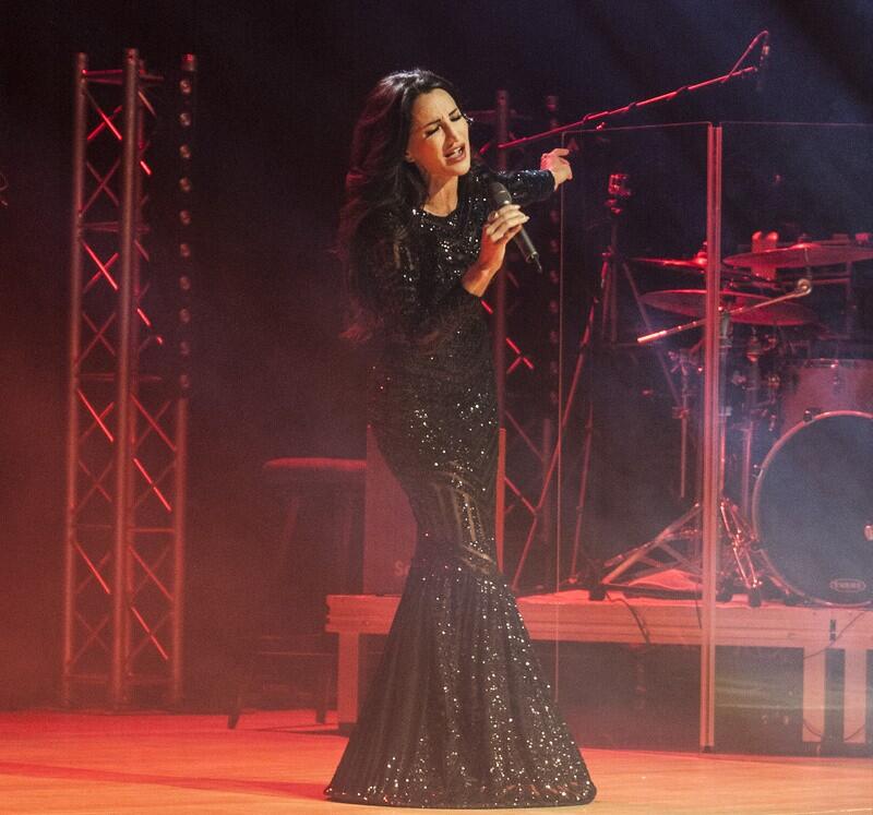 na scenie widać piosenkarkę w czarnej długiej eleganckiej sukni, śpiewa do mikrofonu