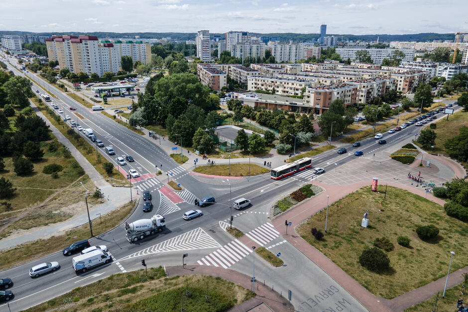 Zdjęcie z lotu ptaka, widok na skrzyżowanie dwóch ulic, po których jeżdżą pojazdy.
