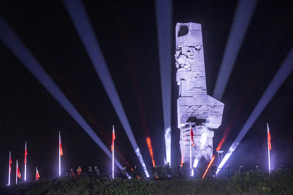 Pomnik Obrońców Wybrzeża na Westerplatte rozświetlony podczas uroczystości przed wschodem słońca.