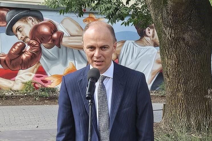 Łysawy mężczyzna w średnim wieku mówi do mikrofonu