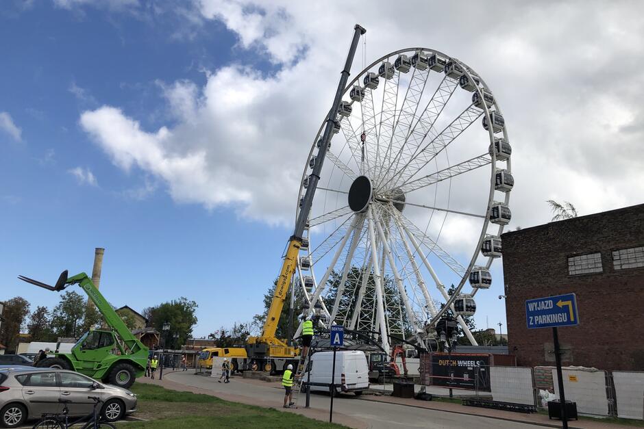 Koło i stojący przy nim bardzo wysoki dźwig samochodowy