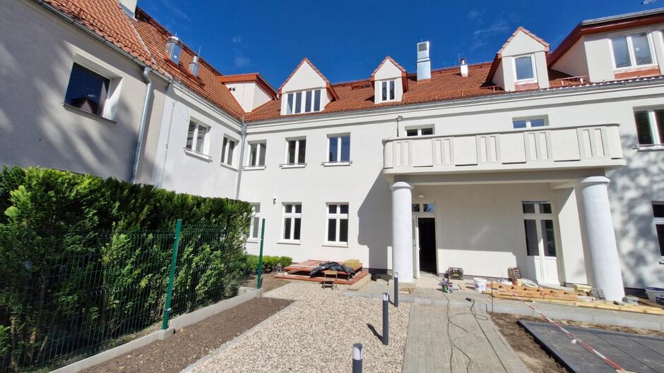 na zdjęciu zabytkowa kamienica trzykondygnacyjna z białą elewacją