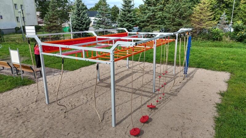 na zdjęciu konstrukcja do ćwiczeń siłowych, w tym drążki i liny