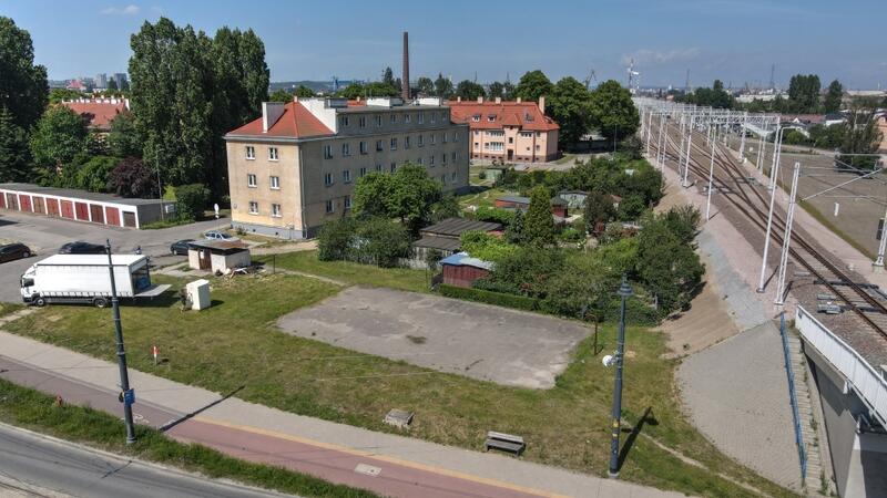 zdjęcie z drona, na pierwszym planie betonowe boisko, za nim widać niewysokie szare kamienice mieszkalne