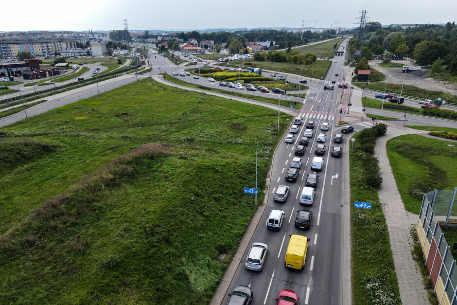 na zdjęciu po lewej szeroki pas zieleni, po prawej widać trzypasmową jednię z samochodami