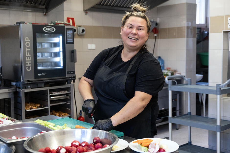 Kucharka w kuchni śmieje się do aparatu.