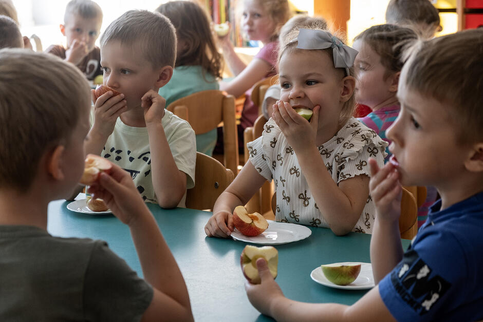 Dzieci w przedszkolu jedzą jabłka.