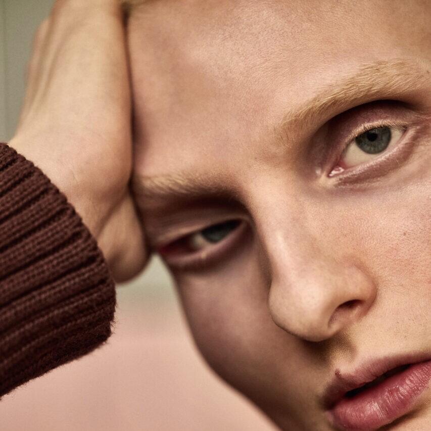 Zdjęcie młodego mężczyzny w zbliżeniu, tak że widać oczy, nos, usta. Widać, że głowa podparta jest ręką