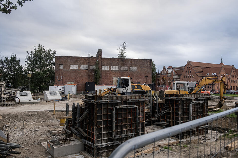 Plac budowy, w tle ceglane budynki.