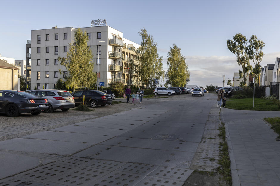 na zdjęciu ulica wyłożona betonowymi płytami, w tle budynki