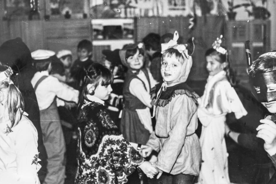 czarnobiałe zdjęcie przedstawia grupę przebranych dzieci bawiących się w klasie