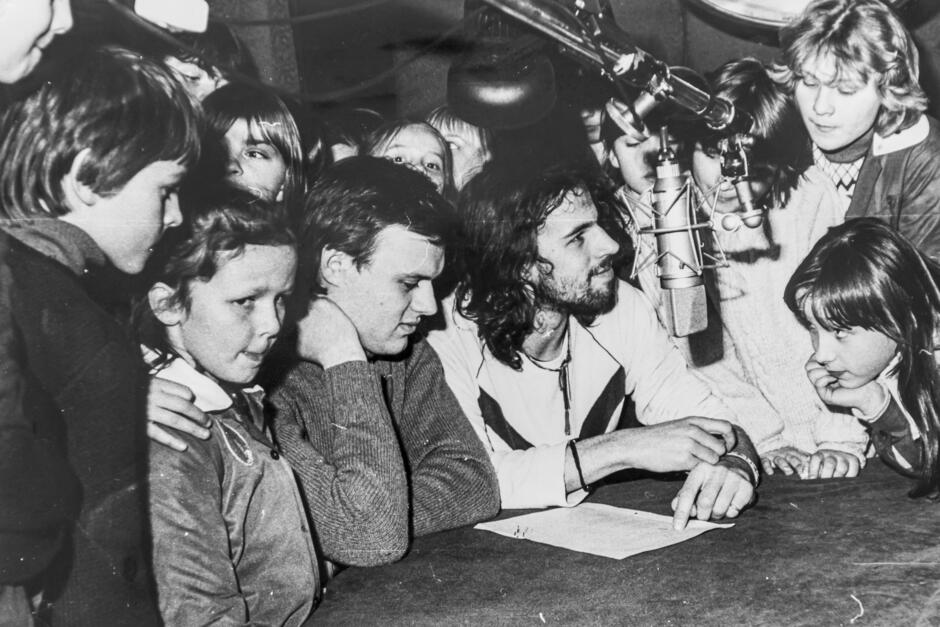 czarnobiałe zdjęcie grupy dzieci przy mikrofonie w studiu