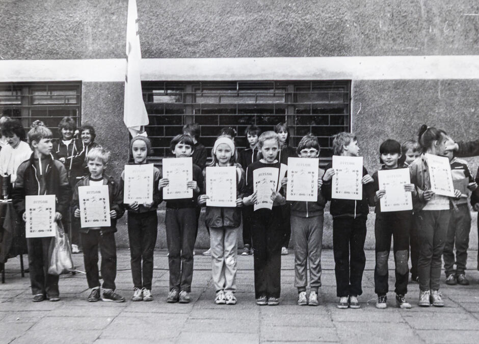 czarnobiałe zdjęcie grupy dzieci trzymających dyplomy 