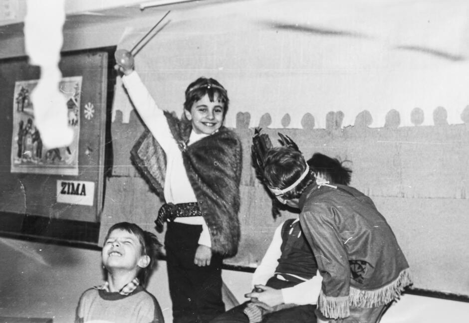 grupa przebranych bawiących się dzieci. W centralnym miejscu chłopiec z szablą w ręce i koroną na głowie