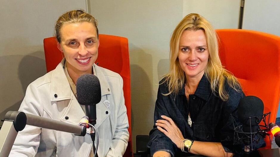 Monika Chabior, zastępczyni Prezydenta Miasta Gdańska oraz Anna Węgrzyn, prezestaka Fundacji Terapia To NIE WSTYD, siedzą w pomarańczowych fotelach za stołem w studiu radiowym, każda przed mikrofonem, gotowe do nagrania rozmowy. Przed nimi stoi monitor komputera, a na stole leżą słuchawki.