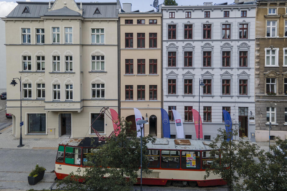 Zabytkowy tramwaj a za nim trzy wyremontowane kamienice