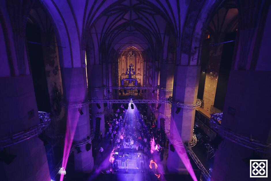 Wnętrze gotyckiego kościoła widziane z poddasza, oświetlone fioletowym światłem.
