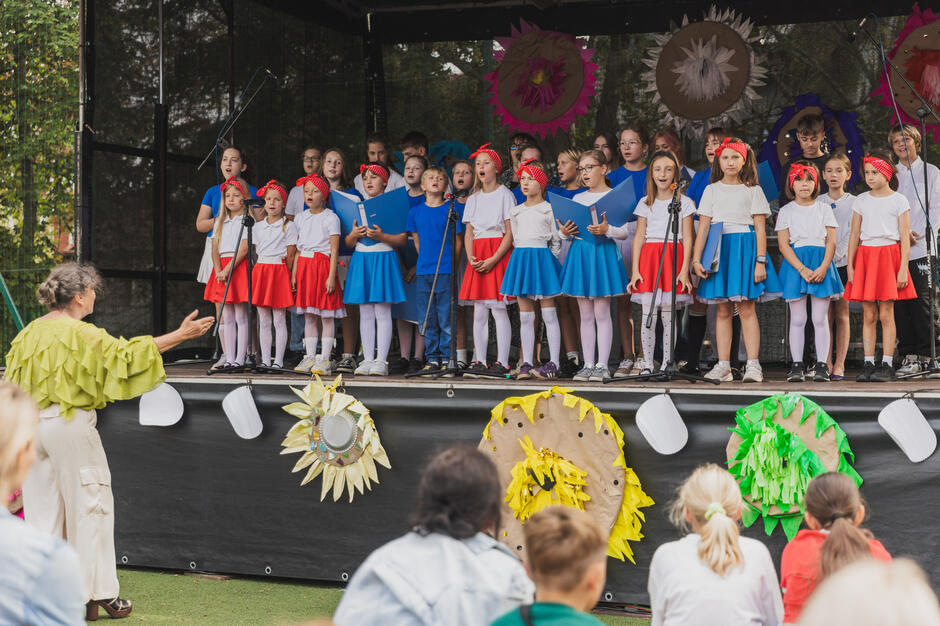 na scenie występuje grupa kilkudziesięciu małych uczniów, śpiewają